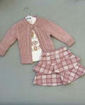 Children's outfit with pink cardigan, white shirt, and plaid skirt on a hanger against a gray background